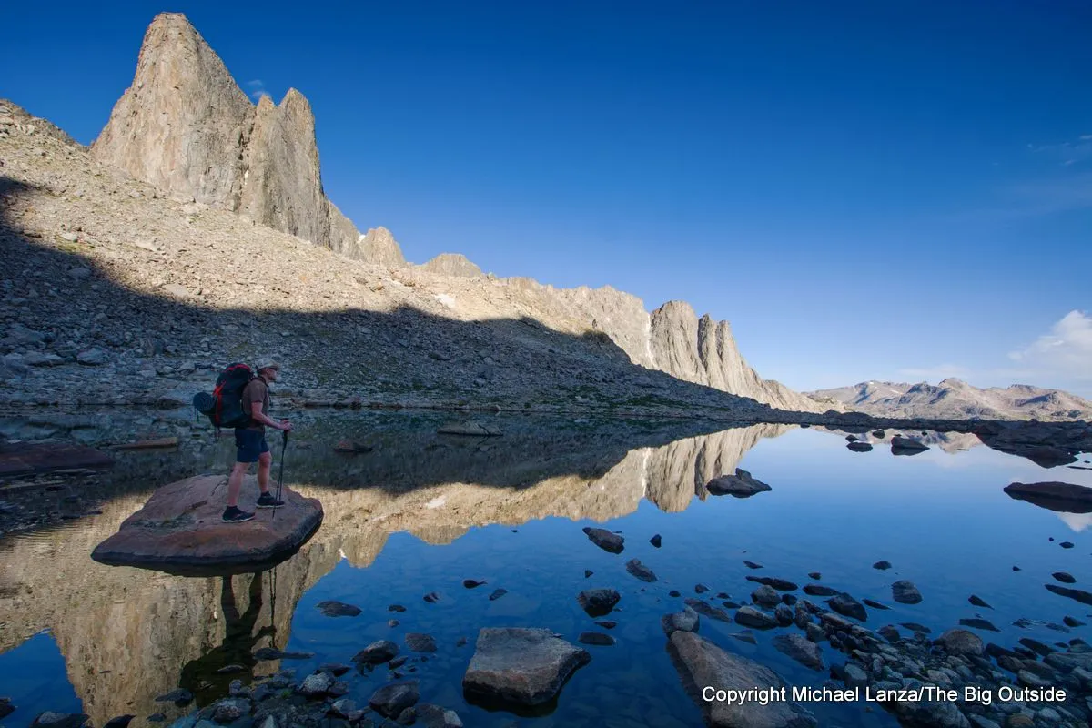 A backpacker at a small tarn in the upper valley of Middle Fork Lake on the Wind River High Route.
