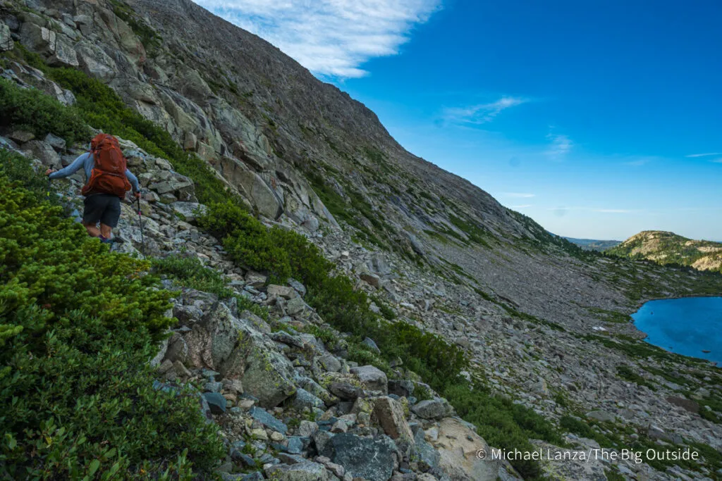 A backpacker hiking above Pyramid Lake in the Wind River Range, Wyoming.