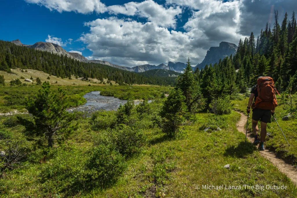 A backpacker hiking the Bears Ears Trail along the South Fork Wind River in the Wind River Range, Wyoming.