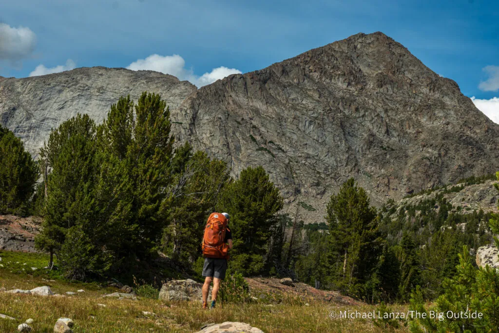 A backpacker hiking the CDT toward Pyramid Peak in the Wind River Range, Wyoming.