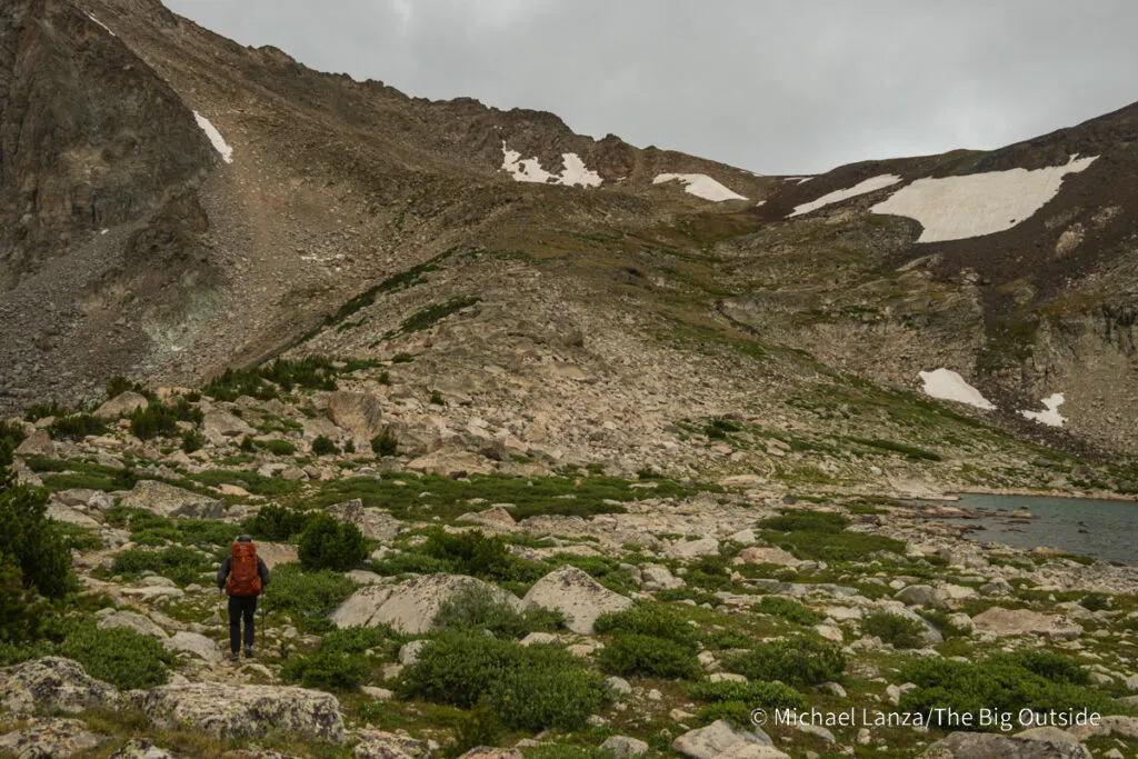 A backpacker hiking toward Washakie Pass in the Wind River Range, Wyoming.