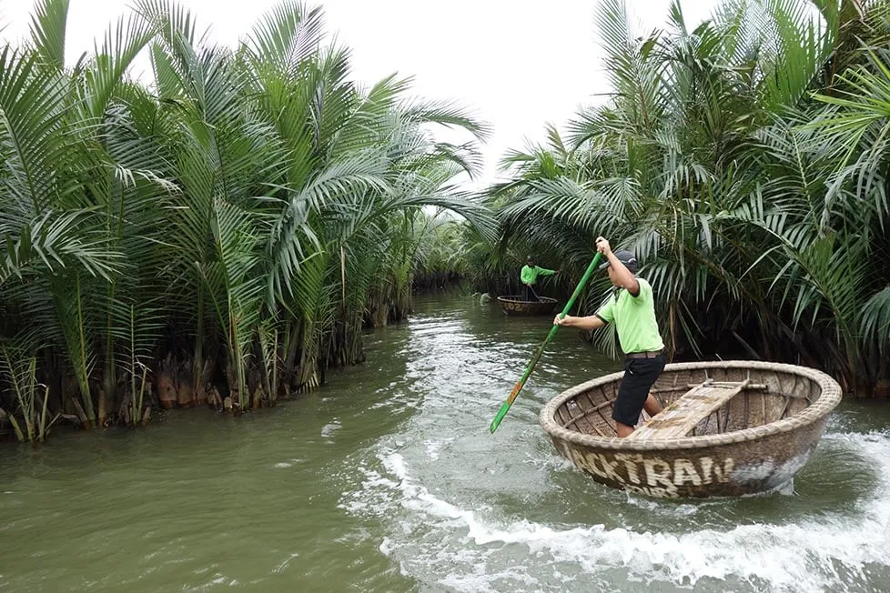 A boat navigating a narrow waterway lined with palm trees in the Mekong Delta, Vietnam.