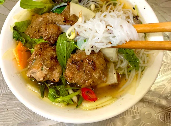A bowl of Bún Chả with grilled pork patties and rice noodles, a popular Hanoi Specialty Food