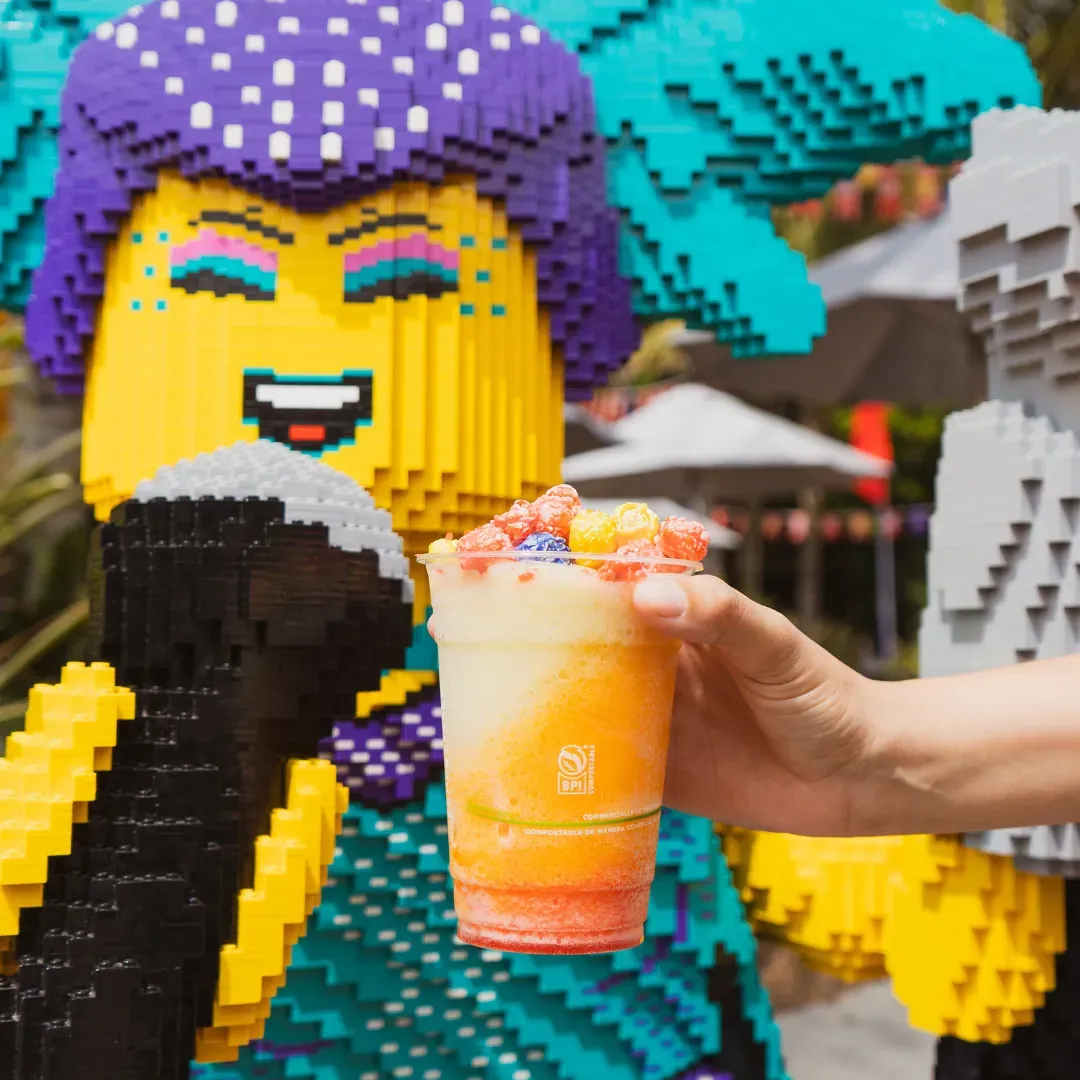 A bright, layered beverage with colorful toppings in a plastic cup.