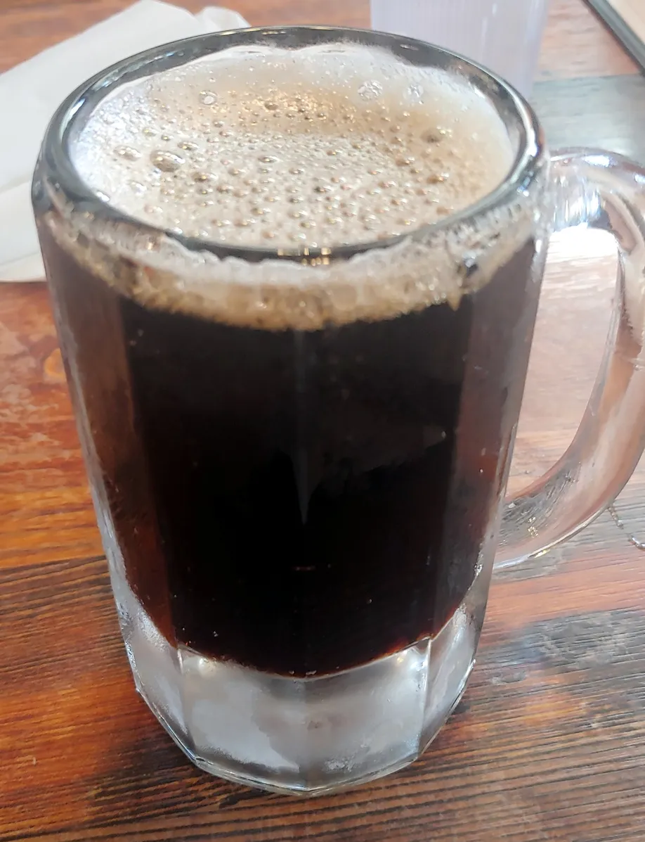 A close-up of a mug filled with a dark beverage and foam