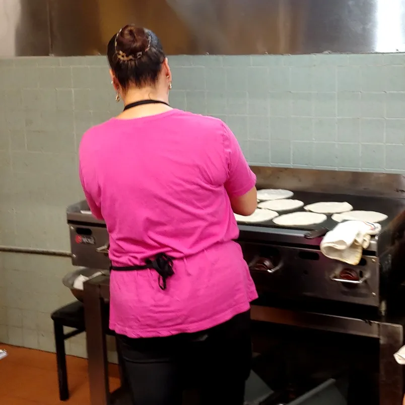 A cook flattening dough for tortillas