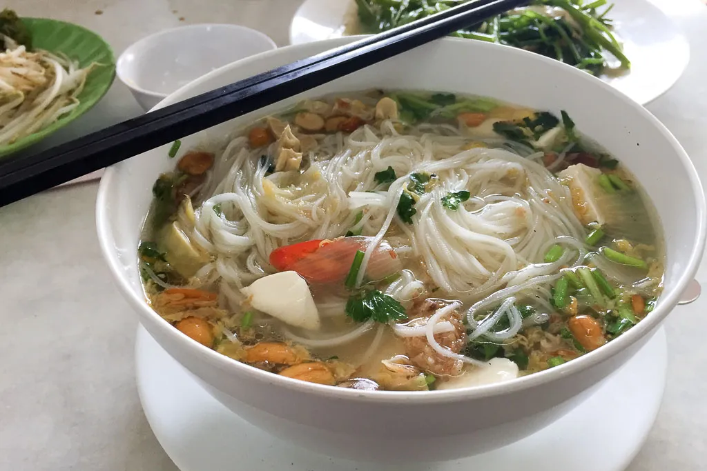 A delicious bowl of vegetarian Pho with various herbs and vegetables