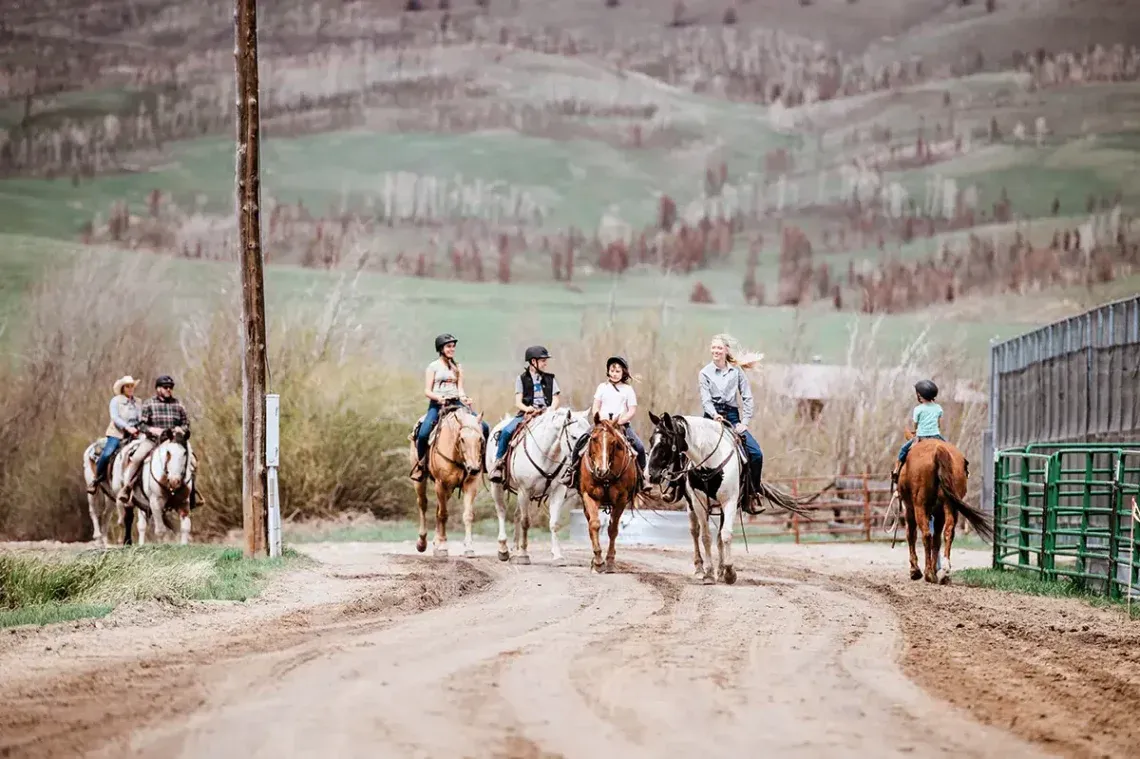 A family returning from a trail ride at C Lazy U Ranch, a type of all inclusive package accessible from Denver