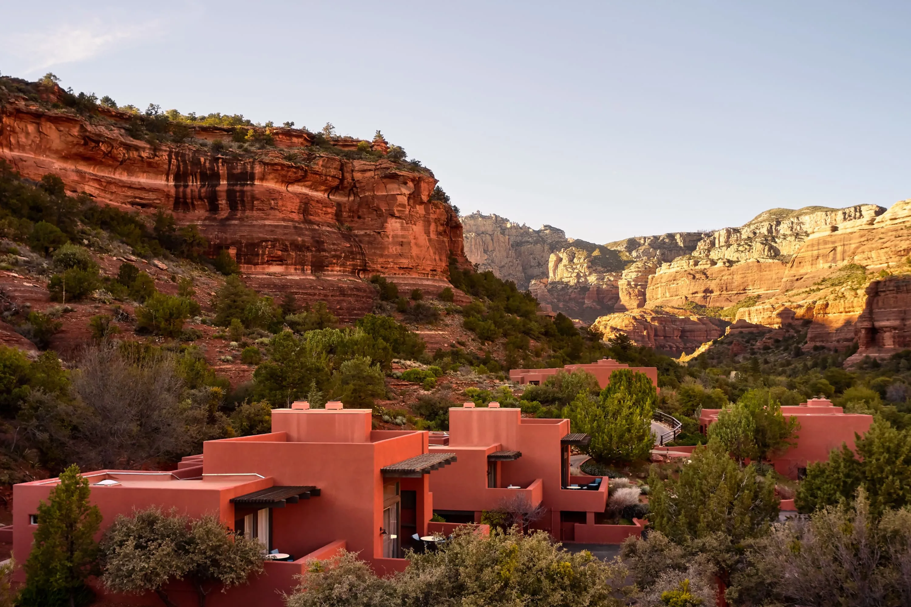 A few pueblo-esque cabins surrounded by lush desert vegetation in a canyon