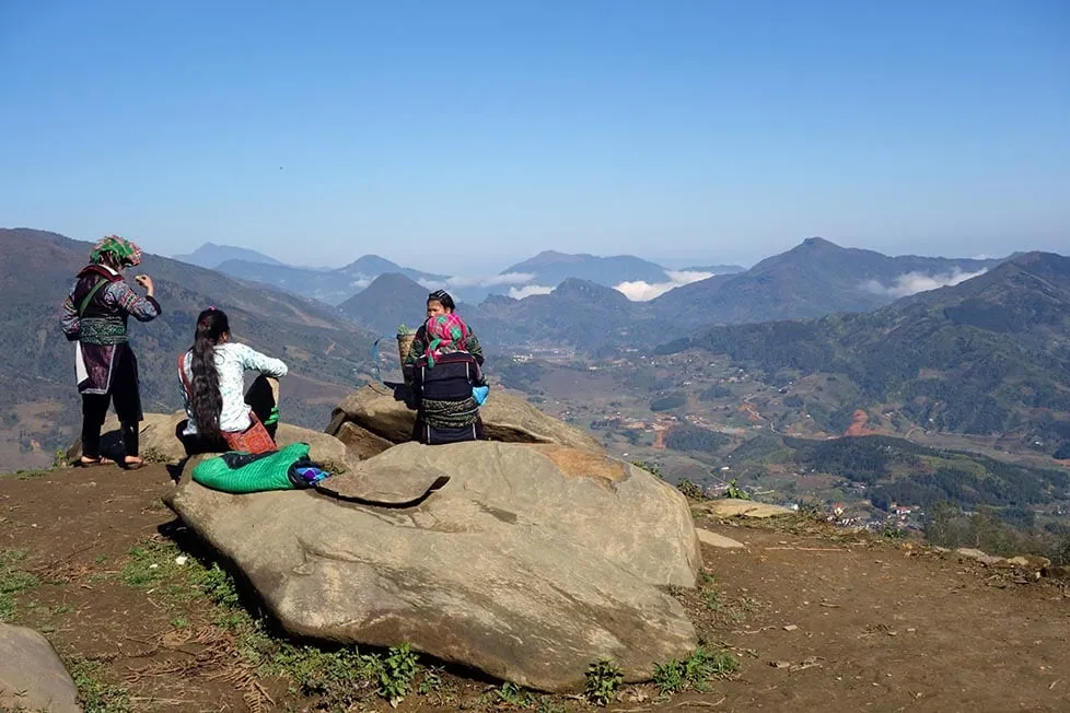 A group hiking with local villagers through terraced rice paddies in Sapa, Vietnam.