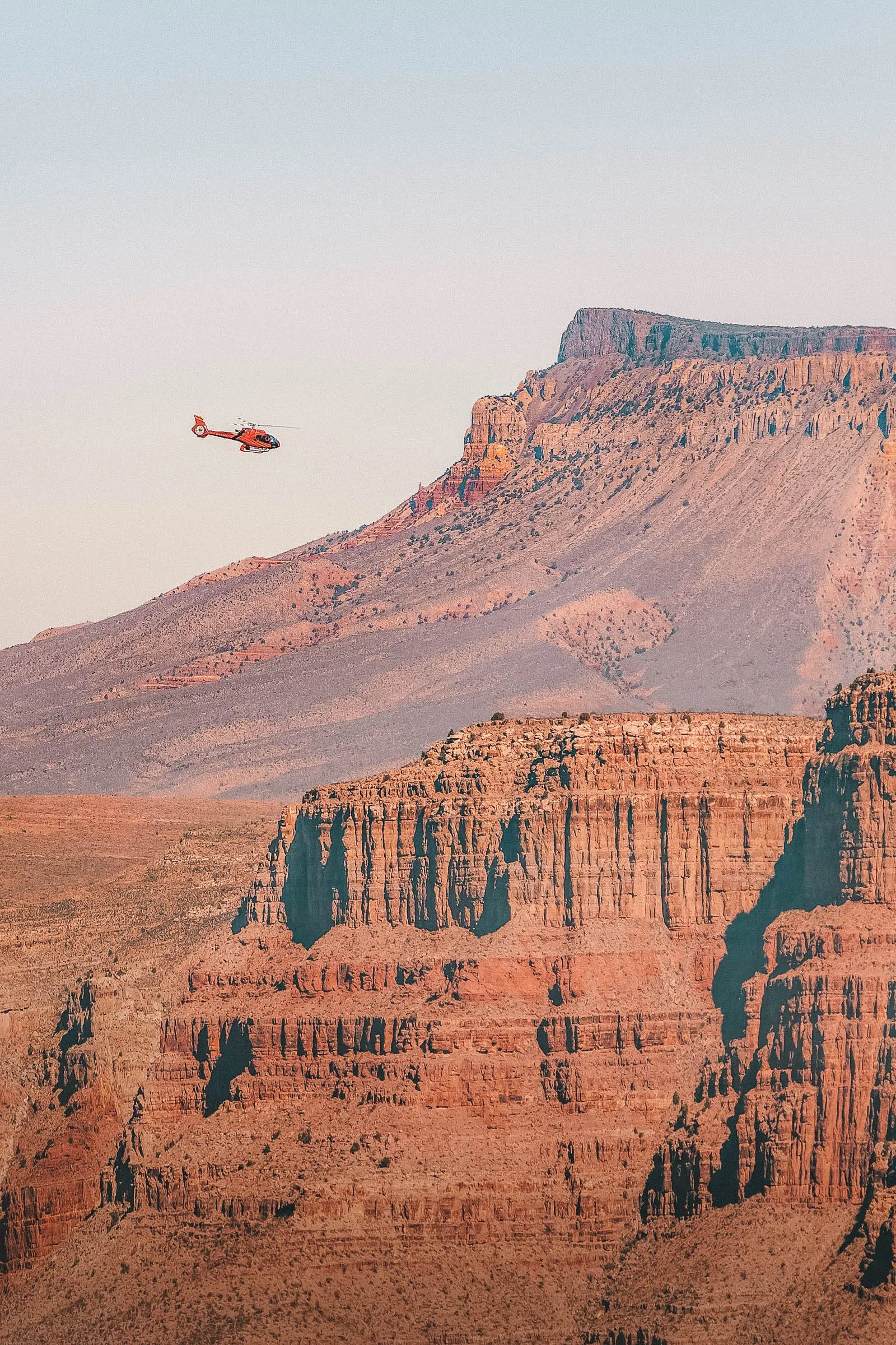 A helicopter flies over the vast landscape of the Grand Canyon
