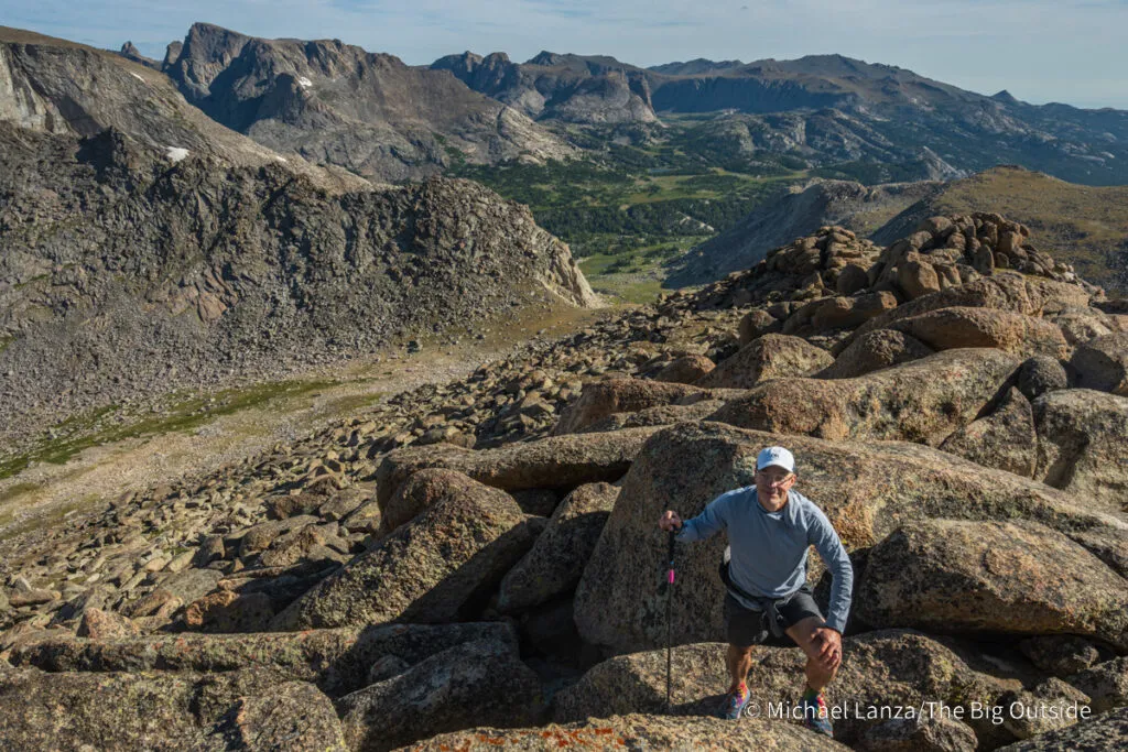 A hiker on Pyramid Peak in the Wind River Range, Wyoming, enjoying the view while Backpacking Wyoming.