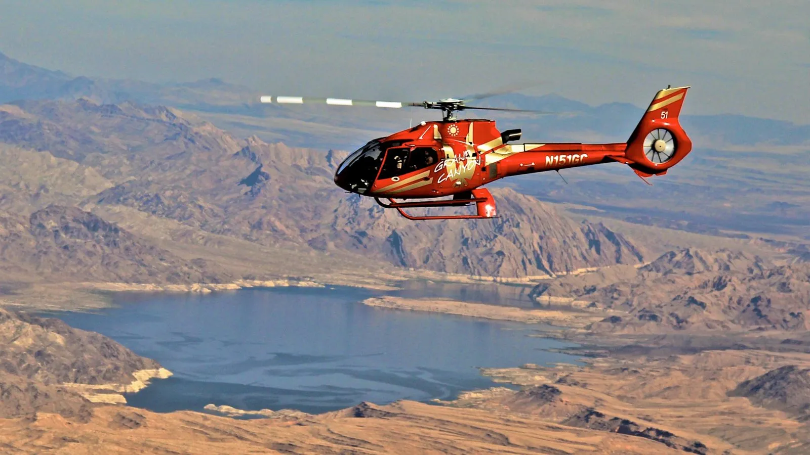 A Papillon helicopter flies over the expansive blue waters of Lake Mead during a las vegas grand canyon helicopter tours.