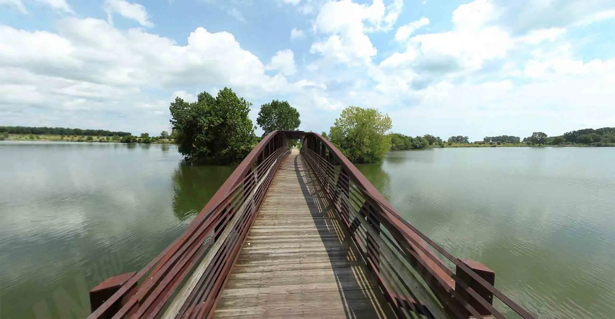A paved trail near water and historical markers, characteristic of the River Raisin Heritage Trail leading to Sterling State Park
