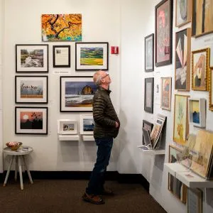 A person looking at framed artwork on display in a Portland art studio