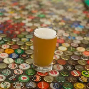 A pint of beer on a bottlecap table, representing Portland's strong craft beer culture and one of the things to do in Portland Oregon