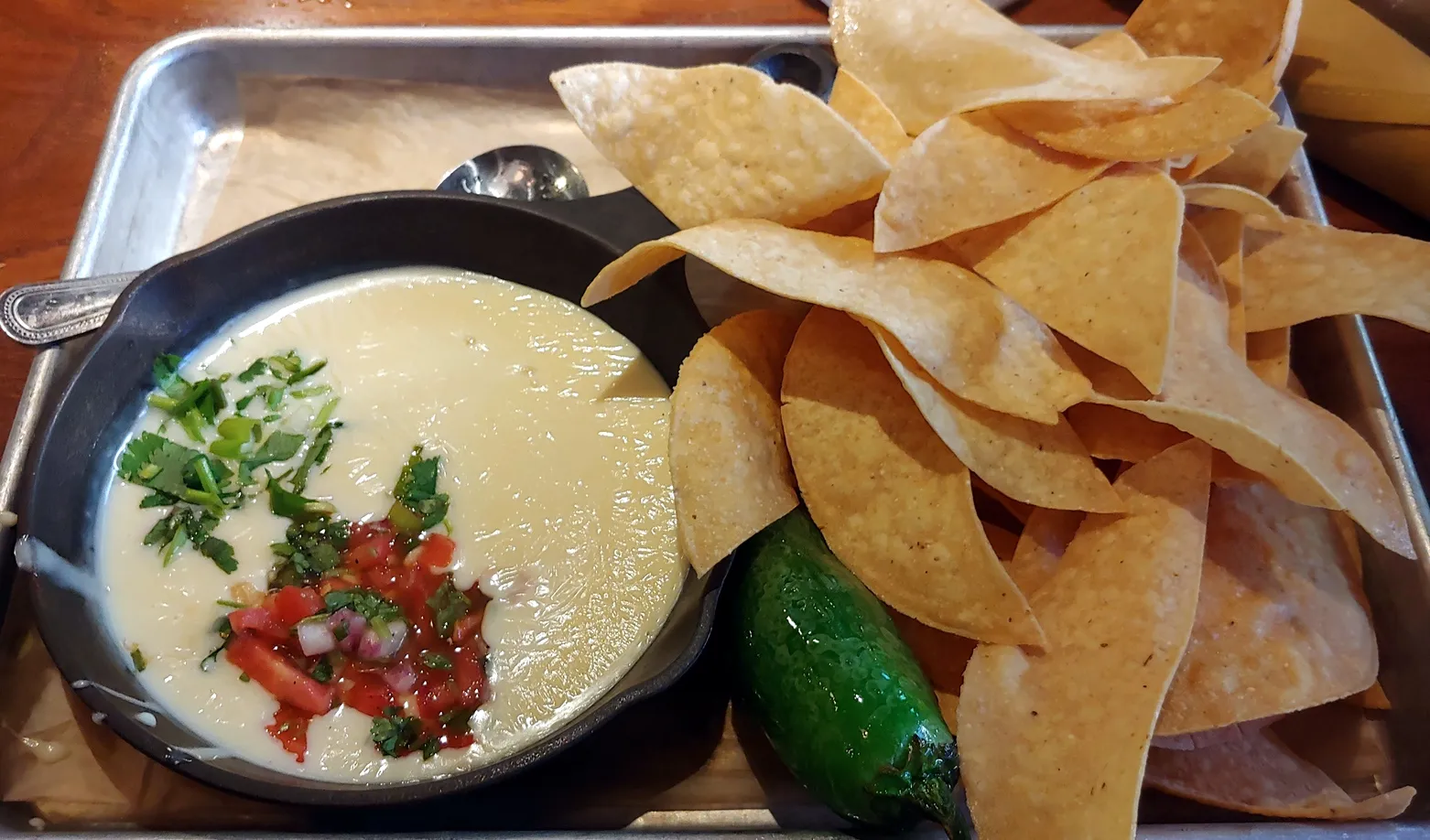 A plate of tortilla chips with a bowl of cheese dip