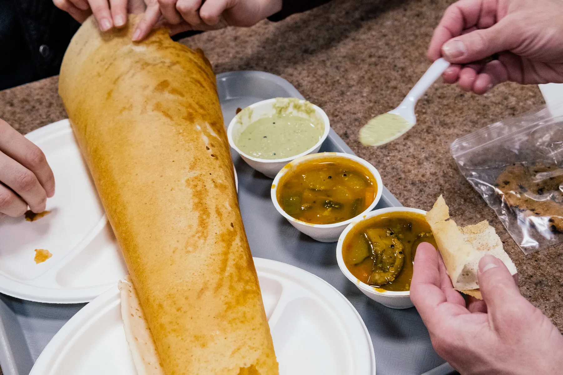 A plate with a large, cone-shaped ghee roast dosa from Temple Canteen.
