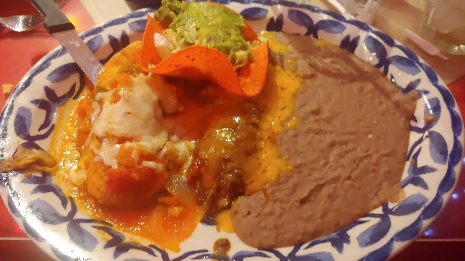 A plate with a large stuffed pepper covered in sauce, rice, and beans