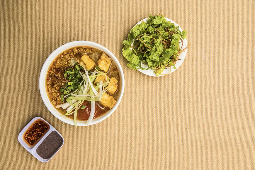 A rich bowl of Vietnam Culinary Bun Rieu with tomato broth and crab cakes