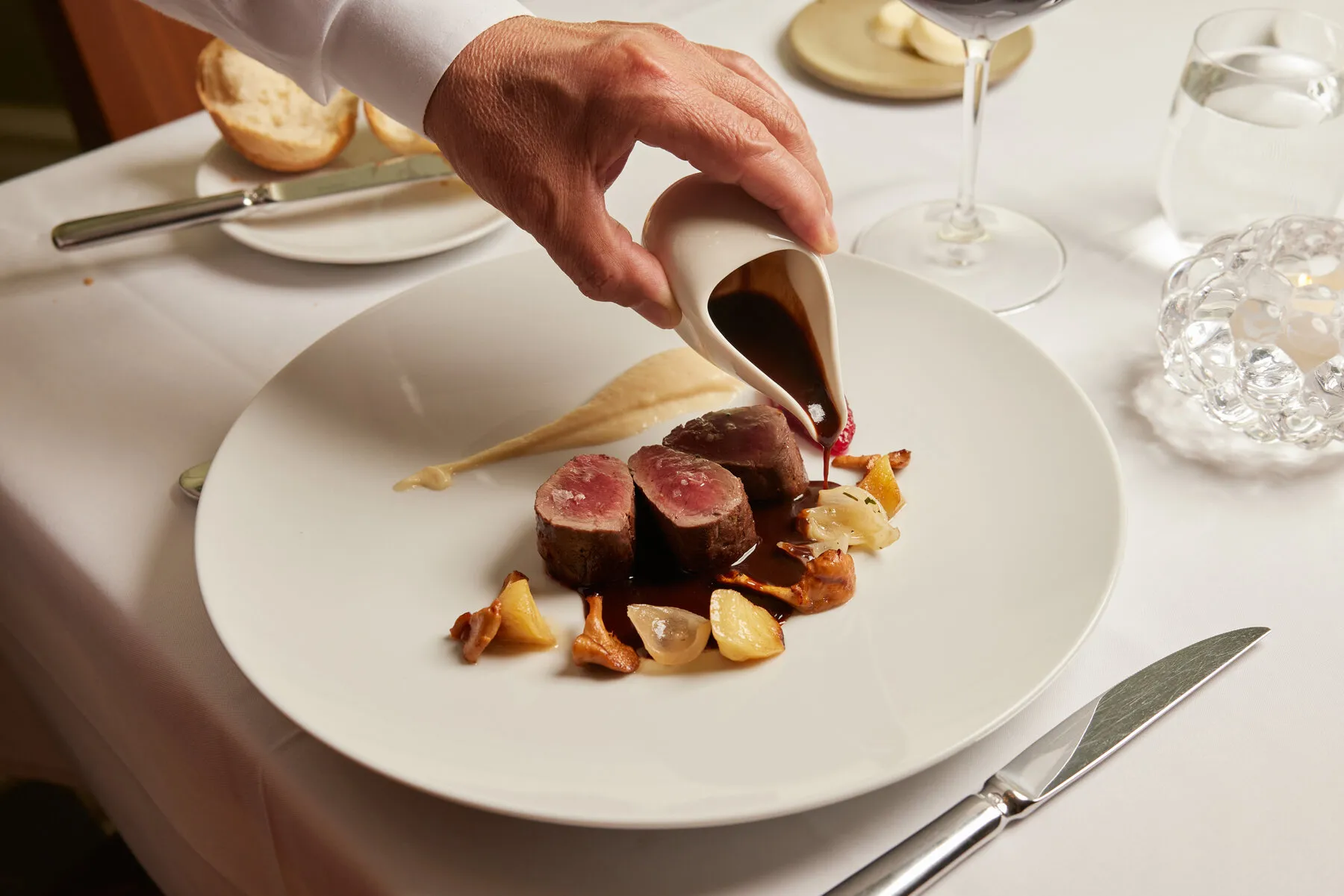 A server pouring sauce over a meat dish at Eulalie, showcasing the restaurant's attention to detail and presentation.