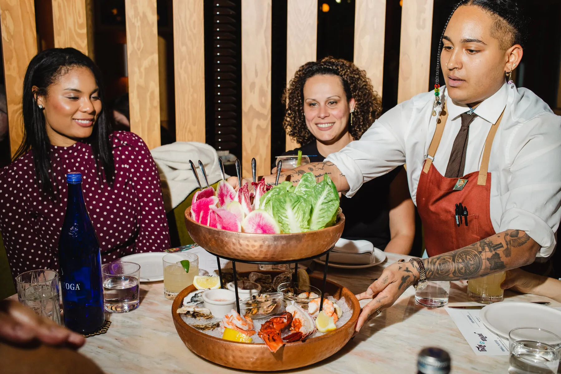 A servers presenting a seafood tower at Hav &amp; Mar, emphasizing the restaurant's focus on seafood and lively service.