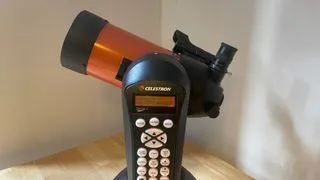 A side view of the Celestron NexStar 4SE amateur astronomy telescope on a wooden table