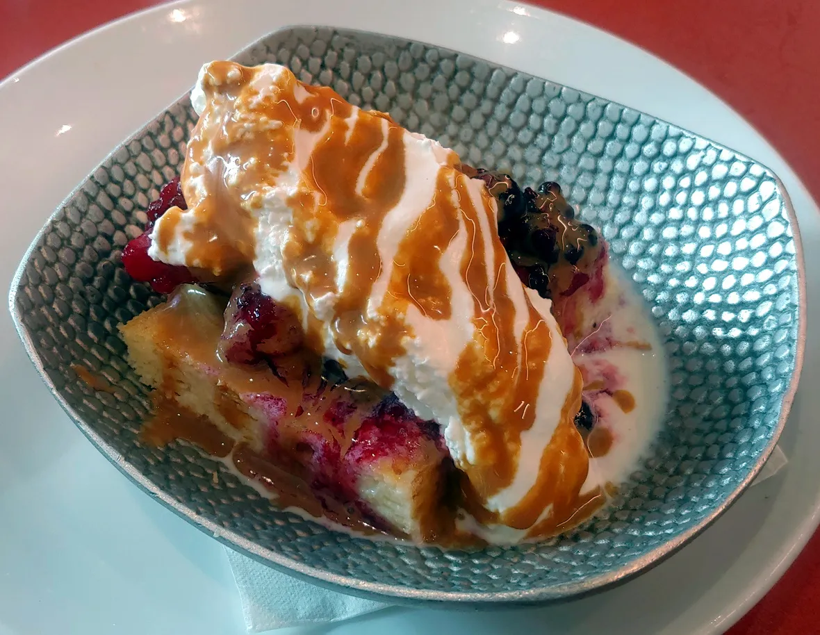 A slice of cake covered in whipped cream and fruit slices