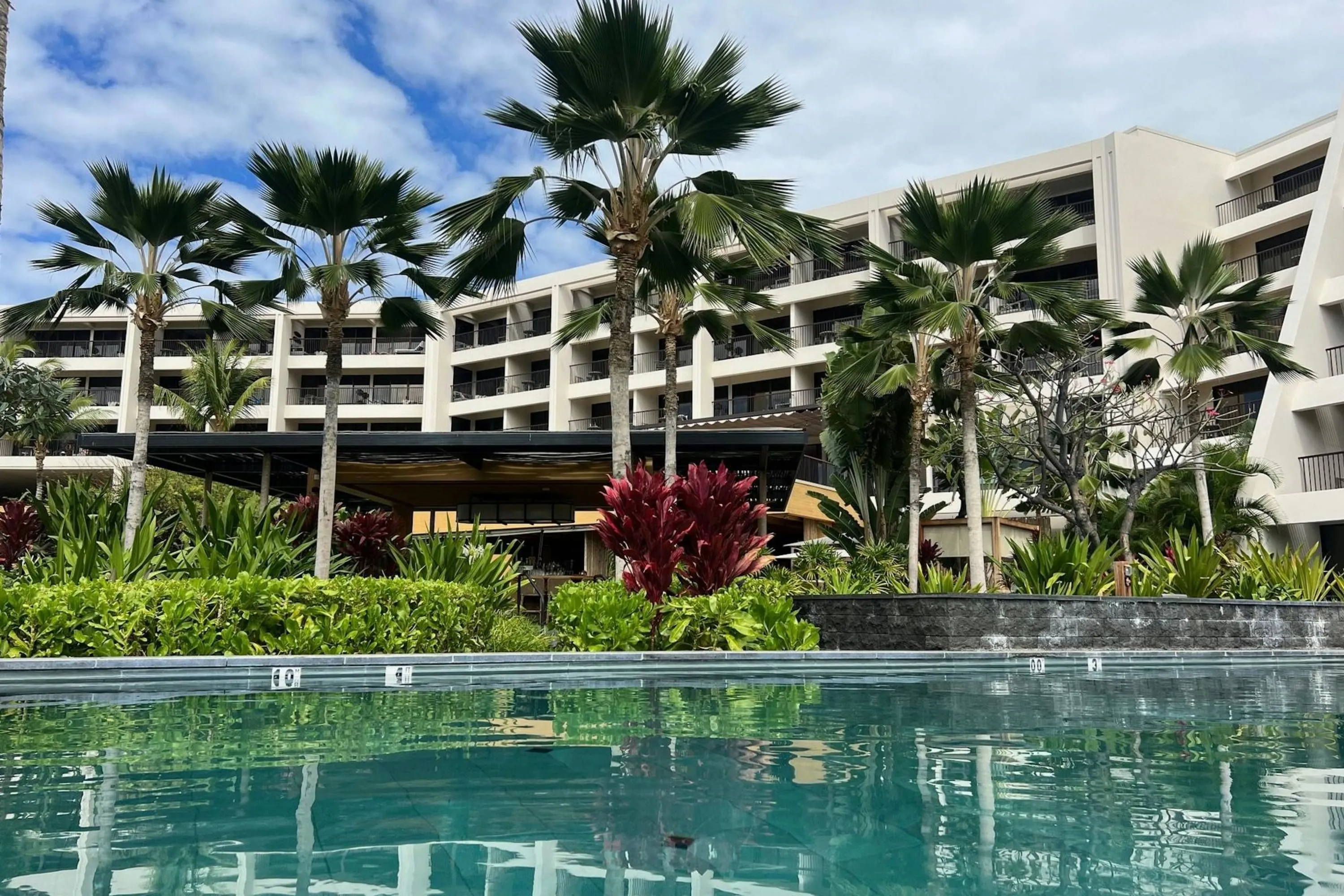 A small water feature leads to a manicured garden before the resort proper
