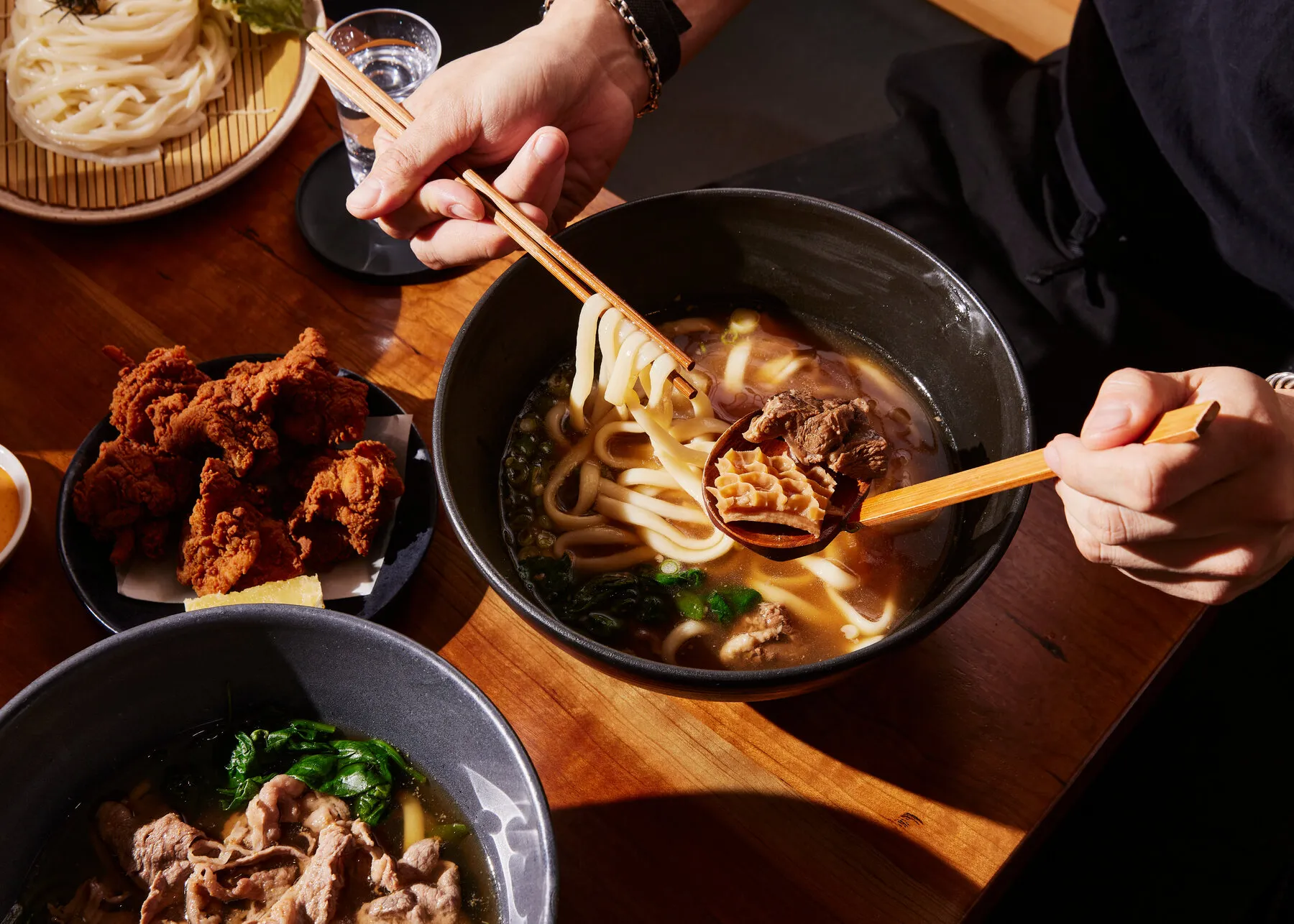 A steaming bowl of udon noodles from Raku, with various toppings and a rich broth.