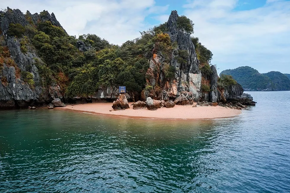 A stunning view of limestone karsts in Ha Long Bay from a beach, showcasing the beautiful landscape.
