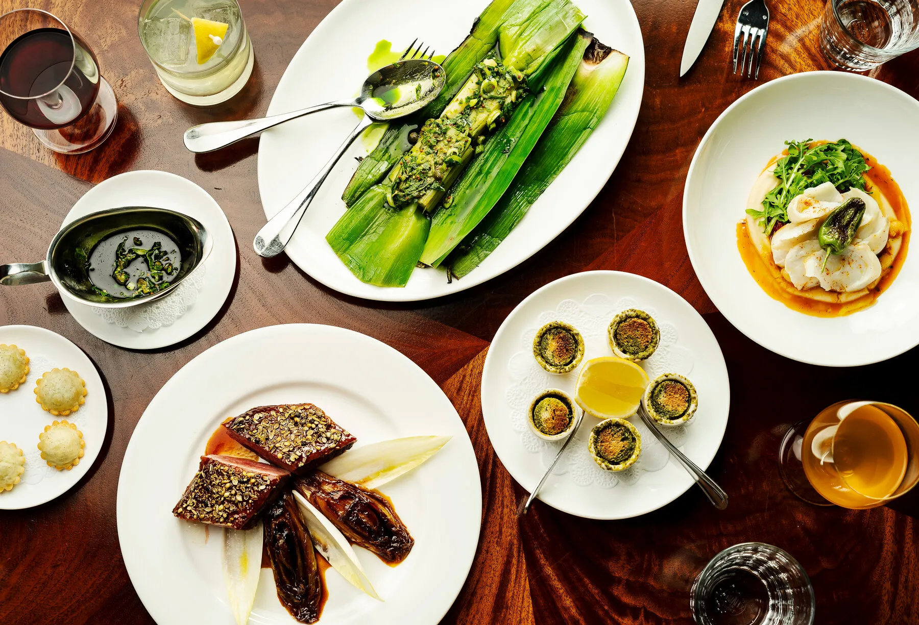 A table spread with classic French dishes from Le Rock, including snails and other appetizers.