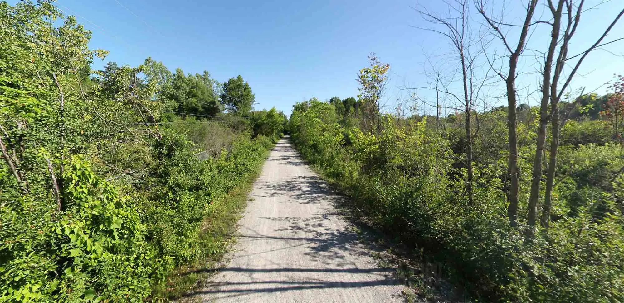 A trail with a mixed surface, passing through a suburban or rural landscape, part of the Polly Ann Trail