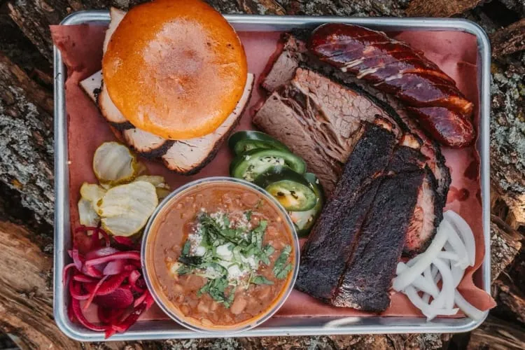 A trio platter of ribs, brisket and sausage, perfect for experiencing Texas BBQ in Arlington