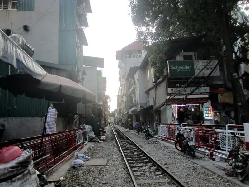 A vibrant scene of the famous Hanoi train street as locals and tourists watch a train pass - what to do in Vietnam