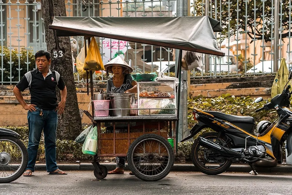 A Vietnamese woman preparing food at a street food stall.