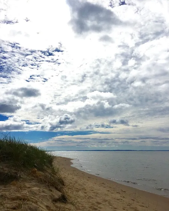 A wide sandy beach along the Lake Michigan shoreline in the Upper Peninsula, perfect for swimming, relaxing, and exploring the vast coastline.