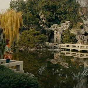 A woman photographs a traditional Chinese garden with a pond, part of the cultural fun things to do in Portland