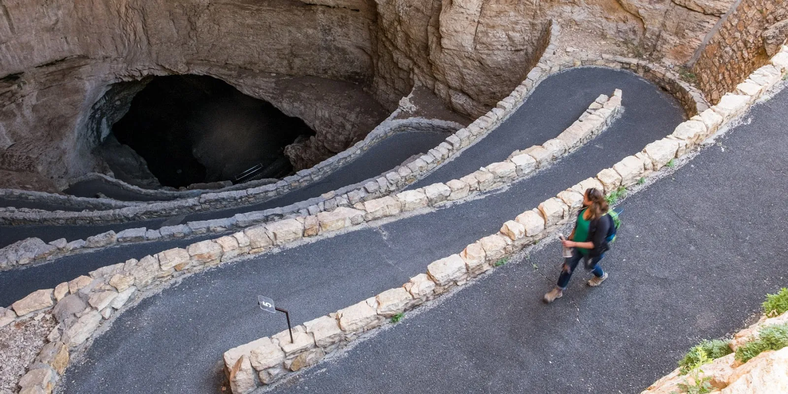 Alt text: Inside Carlsbad Caverns, showing large stalactites hanging from the cave ceiling and stalagmites rising from the floor, illuminated by dim lights.