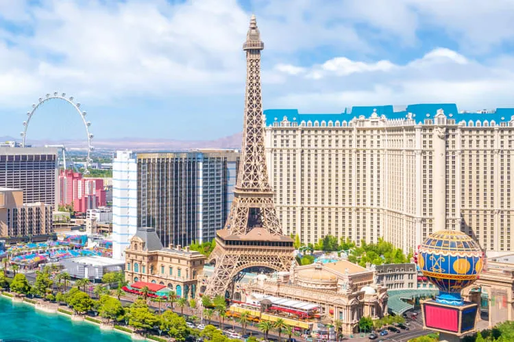 An Eiffel Tower replica next to other buildings and a body of water at the Paris Hotel, ideal for a romantic Las Vegas date night