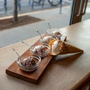 An ice cream sampler with four small bowls and a cone sits on a table, representing delicious food tours in Portland Oregon.