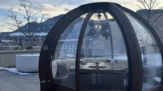 An illuminated Alpenglobe on a rooftop at night, with city lights or mountain views in the background, representing unique dining near Denver.
