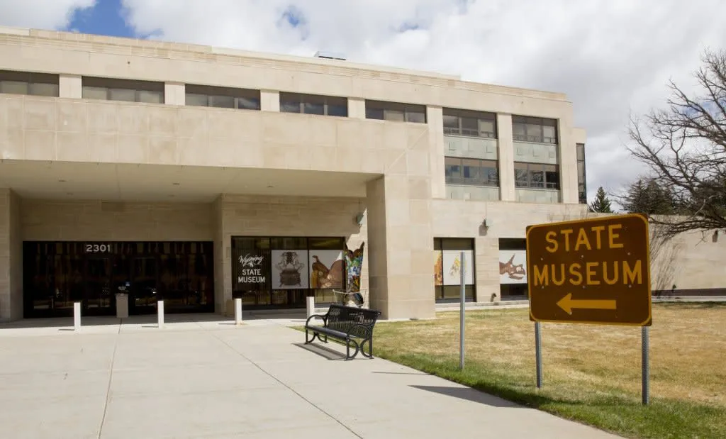 An outside view of the Wyoming State Museum and a sign that reads, 