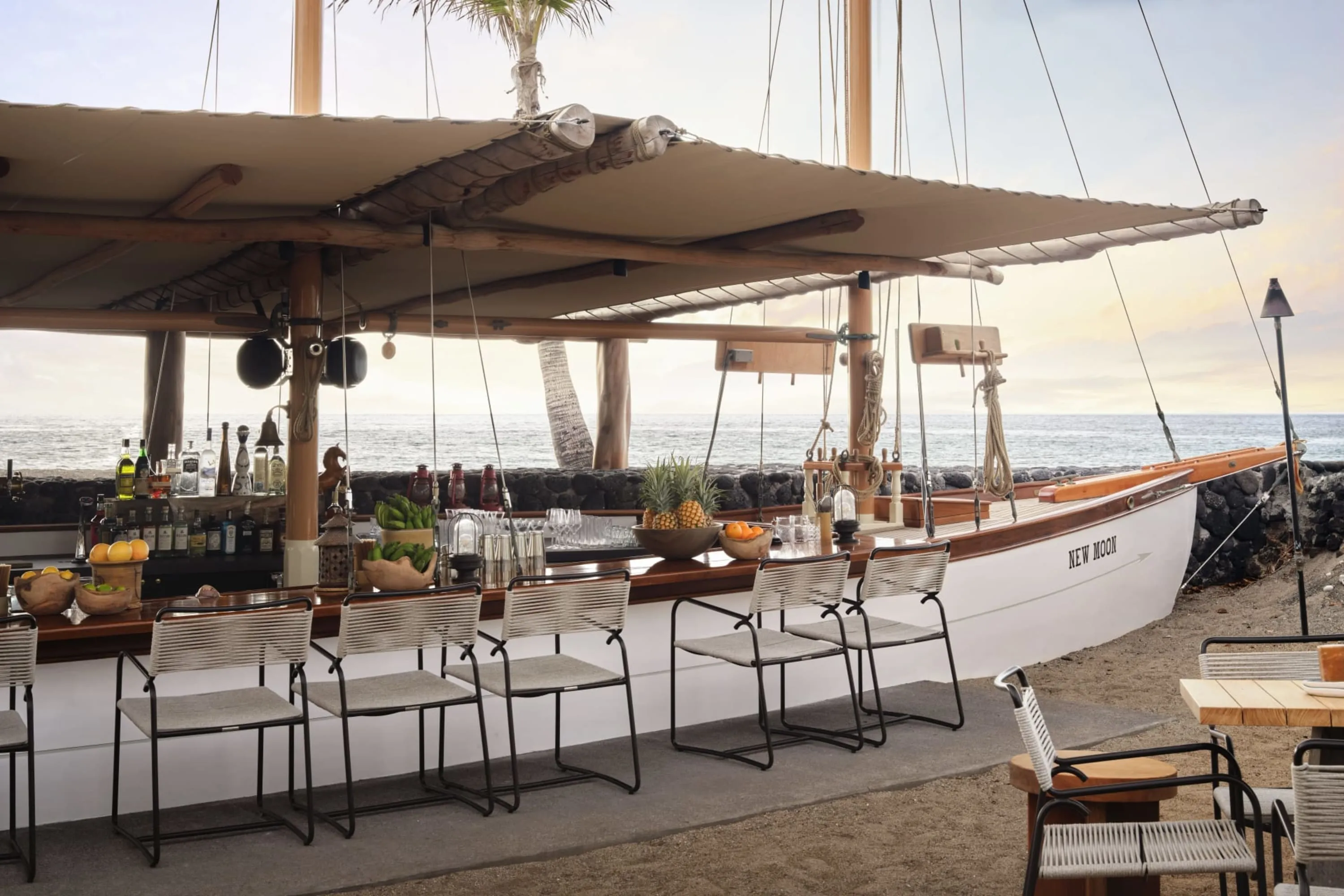 An upscale bar and eatery made out of a sailboat dug deep into the sand on the beach