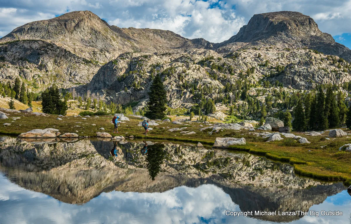 Backpackers hiking past a tarn off the Highline Trail (CDT) in Wyoming
