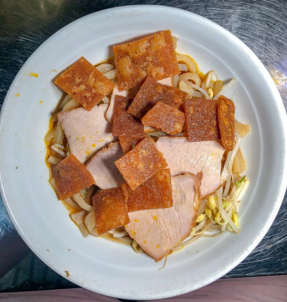 Bowl of Cao Lau noodles with pork, herbs, and crispy bits