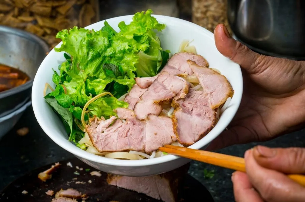Bowl of cao lau topped with char siu