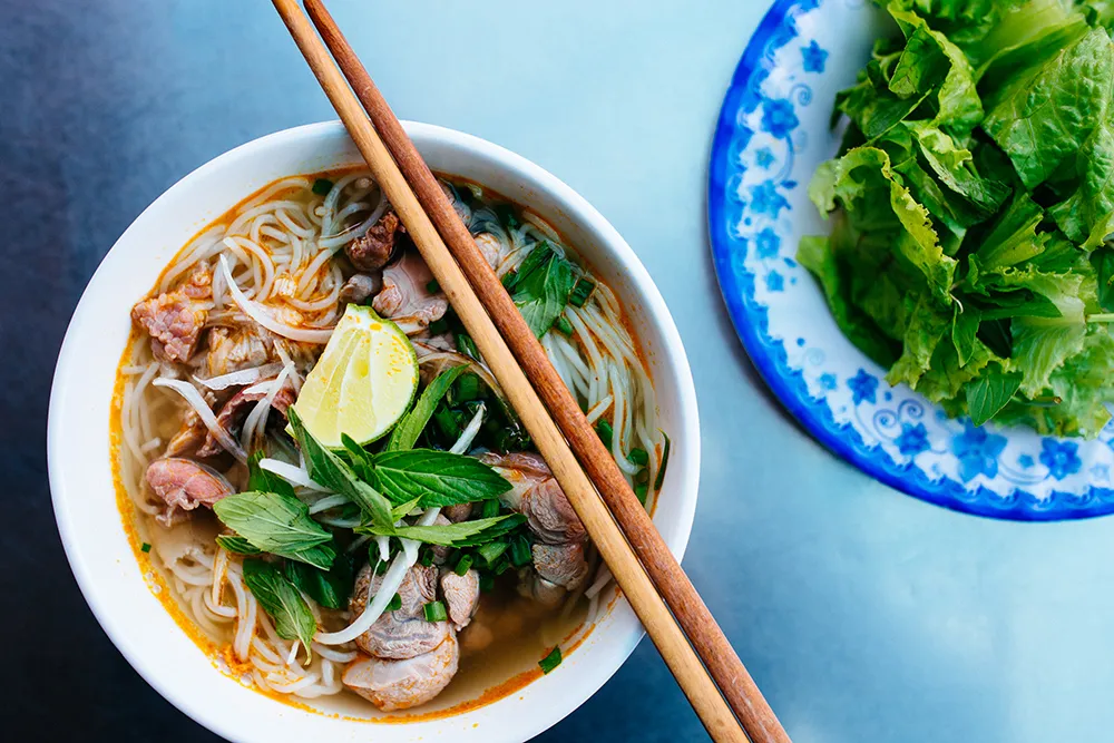 Bun Bo Hue soup with noodles, beef, and sausage in a rich red broth