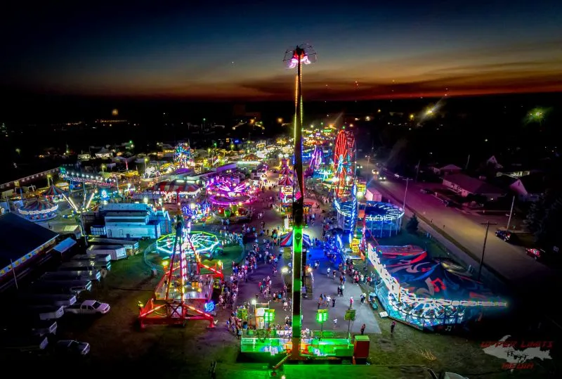 Carnival rides and fairgoers at the Upper Peninsula State Fair