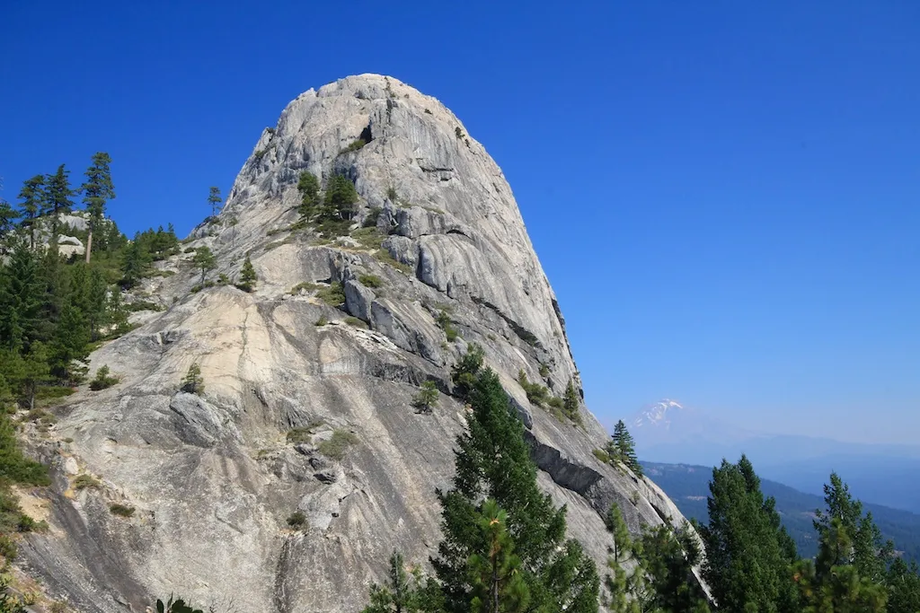 Castle Dome granite formation towers over the forest in Castle Crags State Park with Mt Shasta in the background